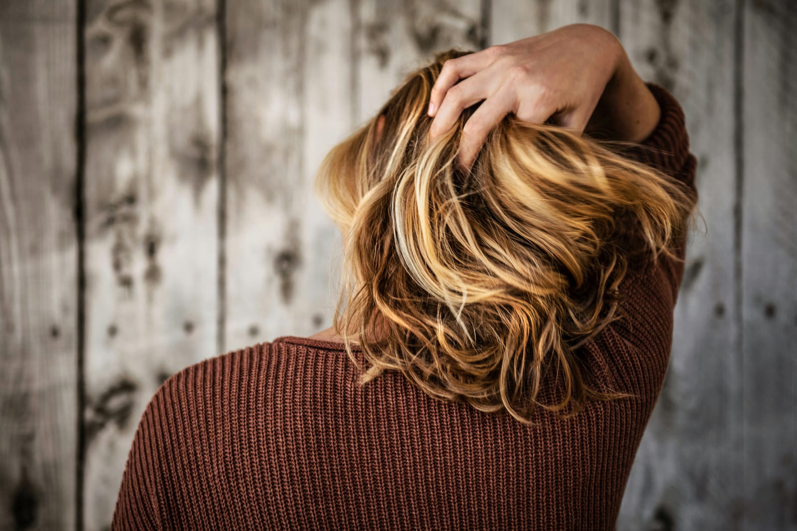 Frau fährt sich in warmem Licht durch ihr blondes Haar
